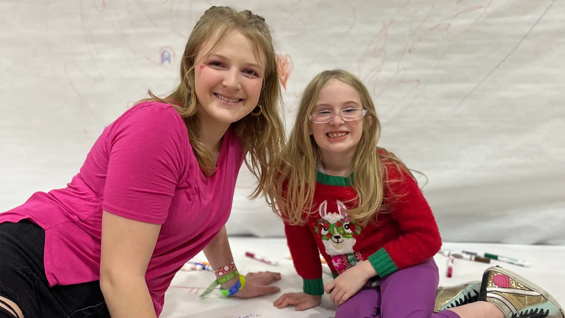 young woman and young girl sitting on the floor smiling at the camera